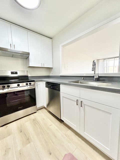 A kitchen with white cabinets and a stainless steel dishwasher.