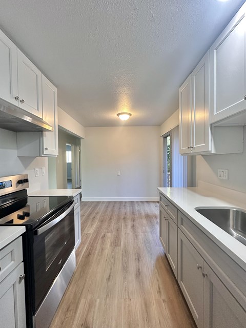 A kitchen with white cabinets and a black stove top oven.