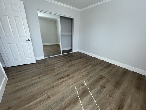 A room with a white door and wooden flooring with white lines drawn on it.