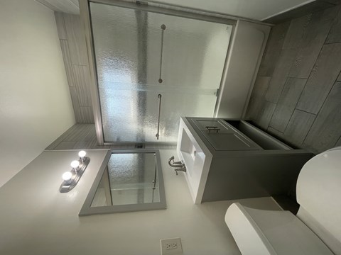 A bathroom with a glass shower door and a glass shelf.