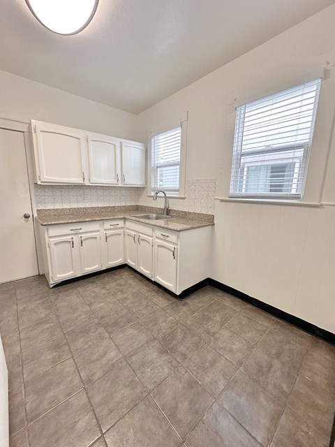 A kitchen with white cabinets and a tiled floor.