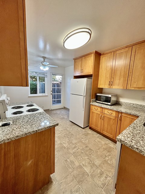 A kitchen with wooden cabinets and a granite countertop.