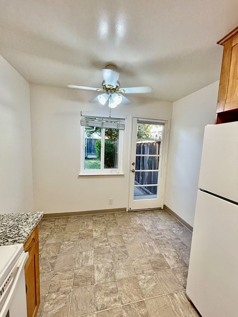 A kitchen with a white refrigerator and a ceiling fan.