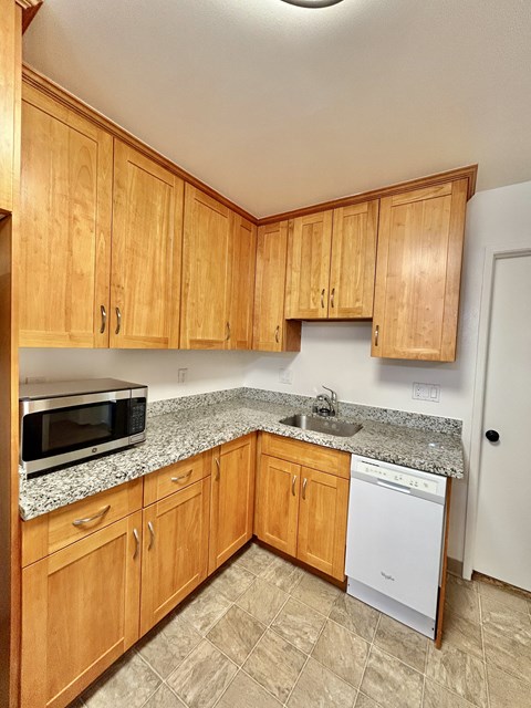 A kitchen with wooden cabinets and a granite countertop.