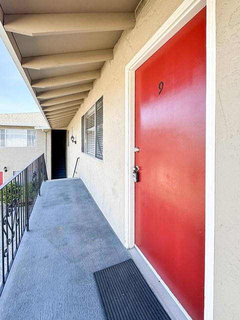 a red door at the entrance to a building with a balcony