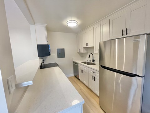 A kitchen with a stainless steel refrigerator and white cabinets.