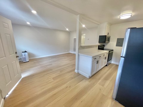 A kitchen with white cabinets and a black fridge.