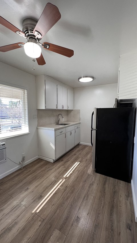 an empty kitchen with white cabinets and a ceiling fan