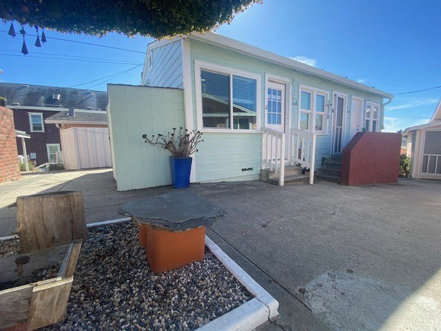 A blue planter sits on a gravel area in front of a house.