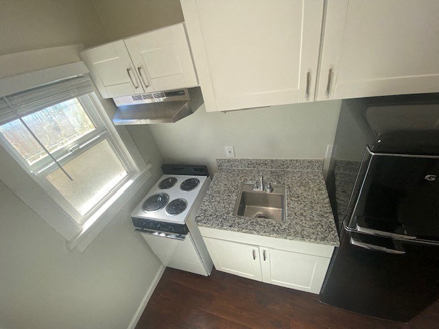 A kitchen with a stove, sink, and cabinets.