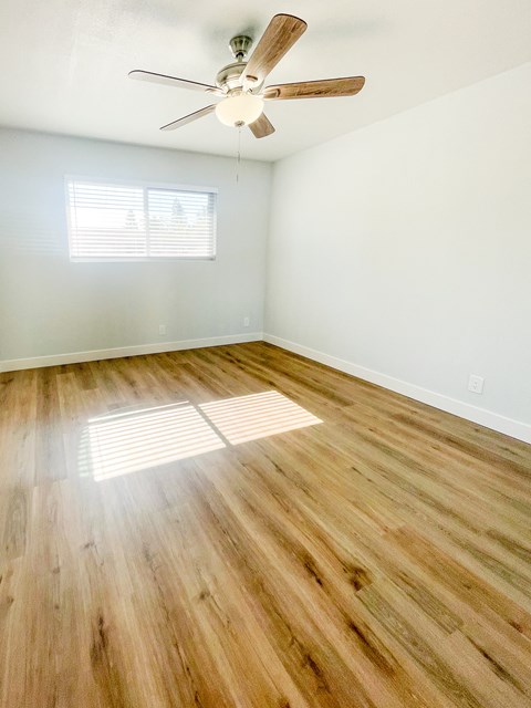 A room with a ceiling fan and wooden flooring.