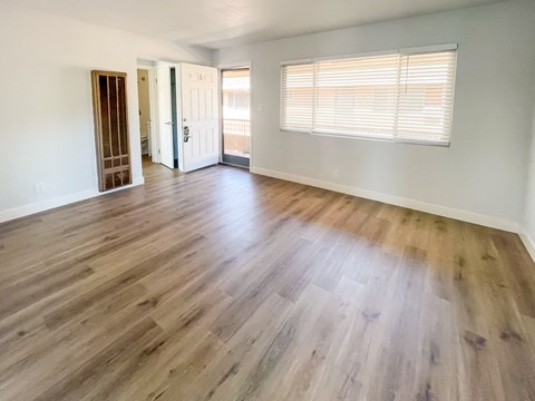 an empty living room with hardwood flooring and a window