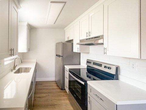 A kitchen with white cabinets and appliances.