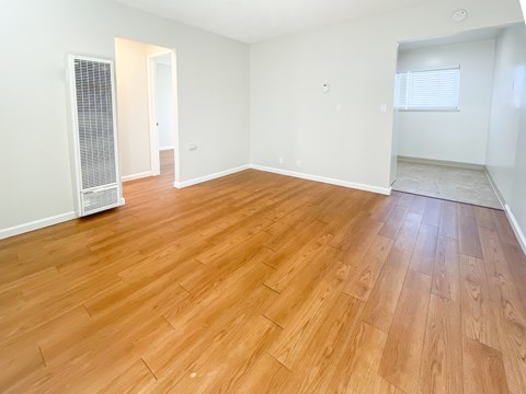 an empty living room with wood flooring and white walls