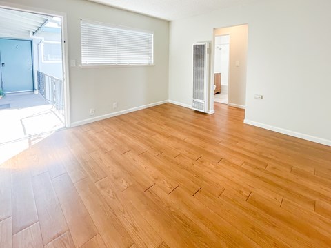 A room with wooden flooring and a window with blinds.