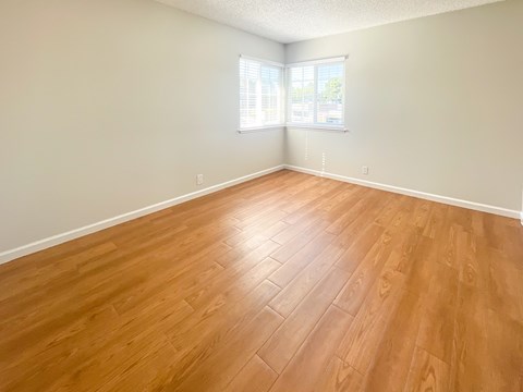 an empty living room with wood floors and a window
