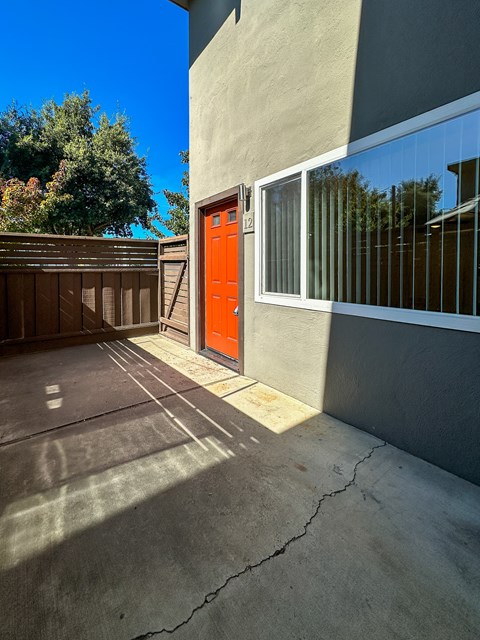 an orange door on a cement building with a driveway