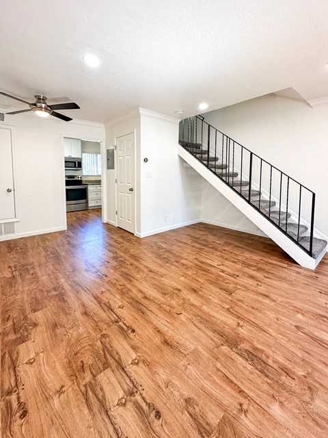 an empty living room with a hard wood floor and a staircase
