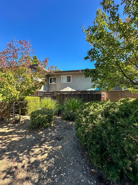 a house with a deck and a yard with bushes and trees