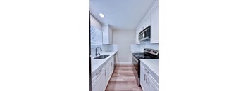 a kitchen with white cabinets and a wood floor
