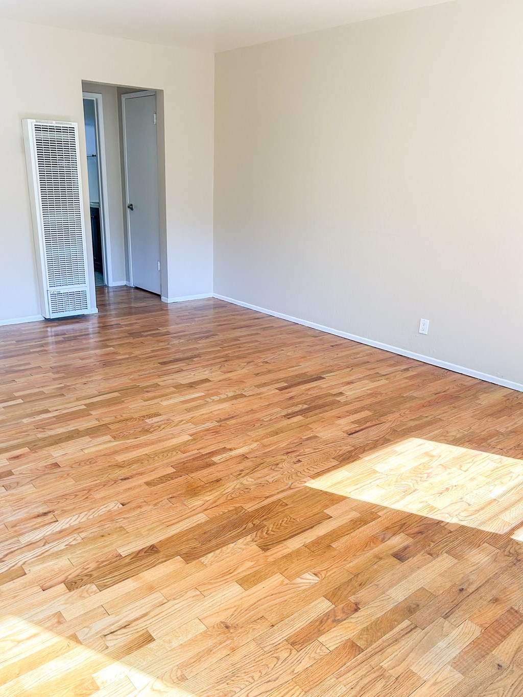an empty living room with wood flooring and white walls