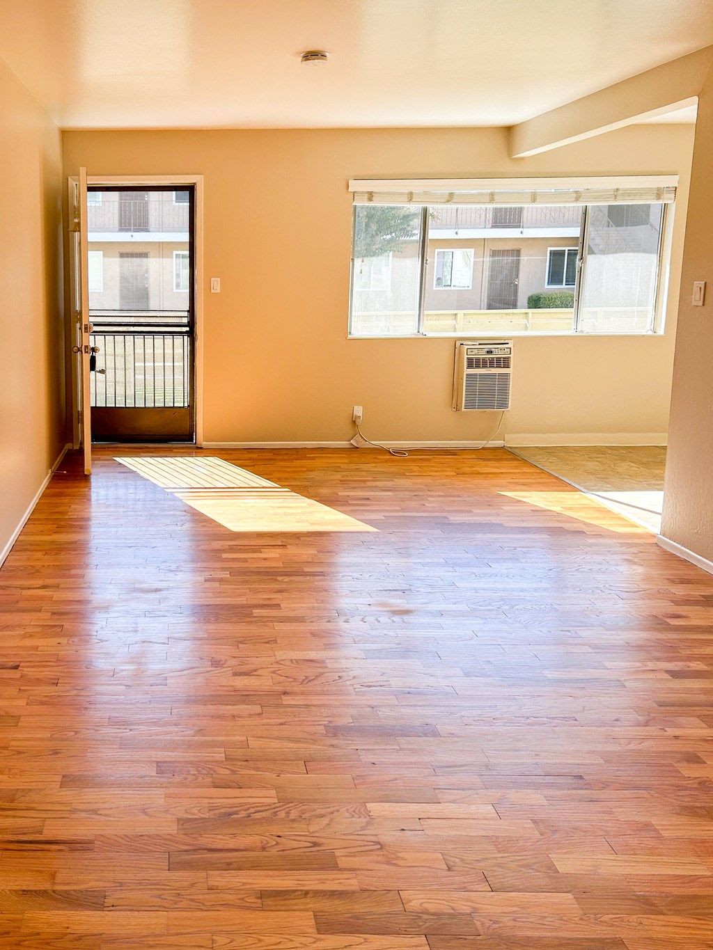 an empty living room with a hard wood floor and two windows