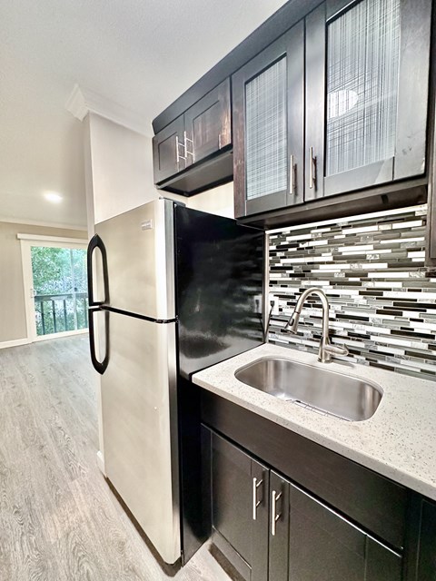 A white refrigerator is in a kitchen with a black counter.