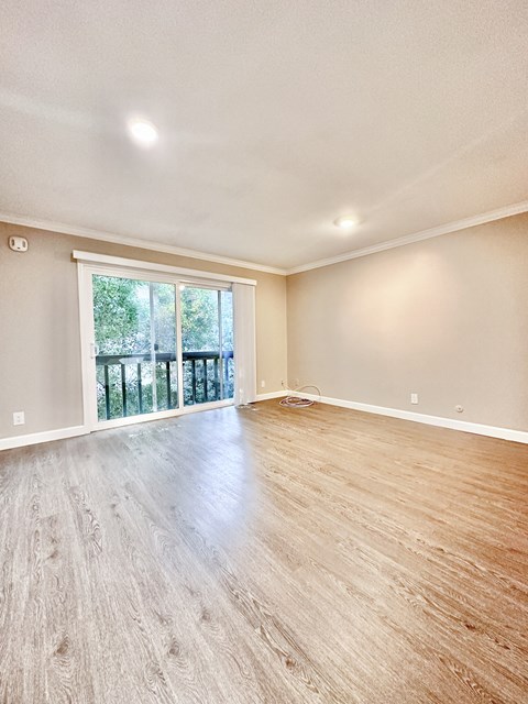 a living room with hardwood floors and a sliding glass door to a balcony