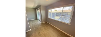 an empty living room with a large window and wooden floors