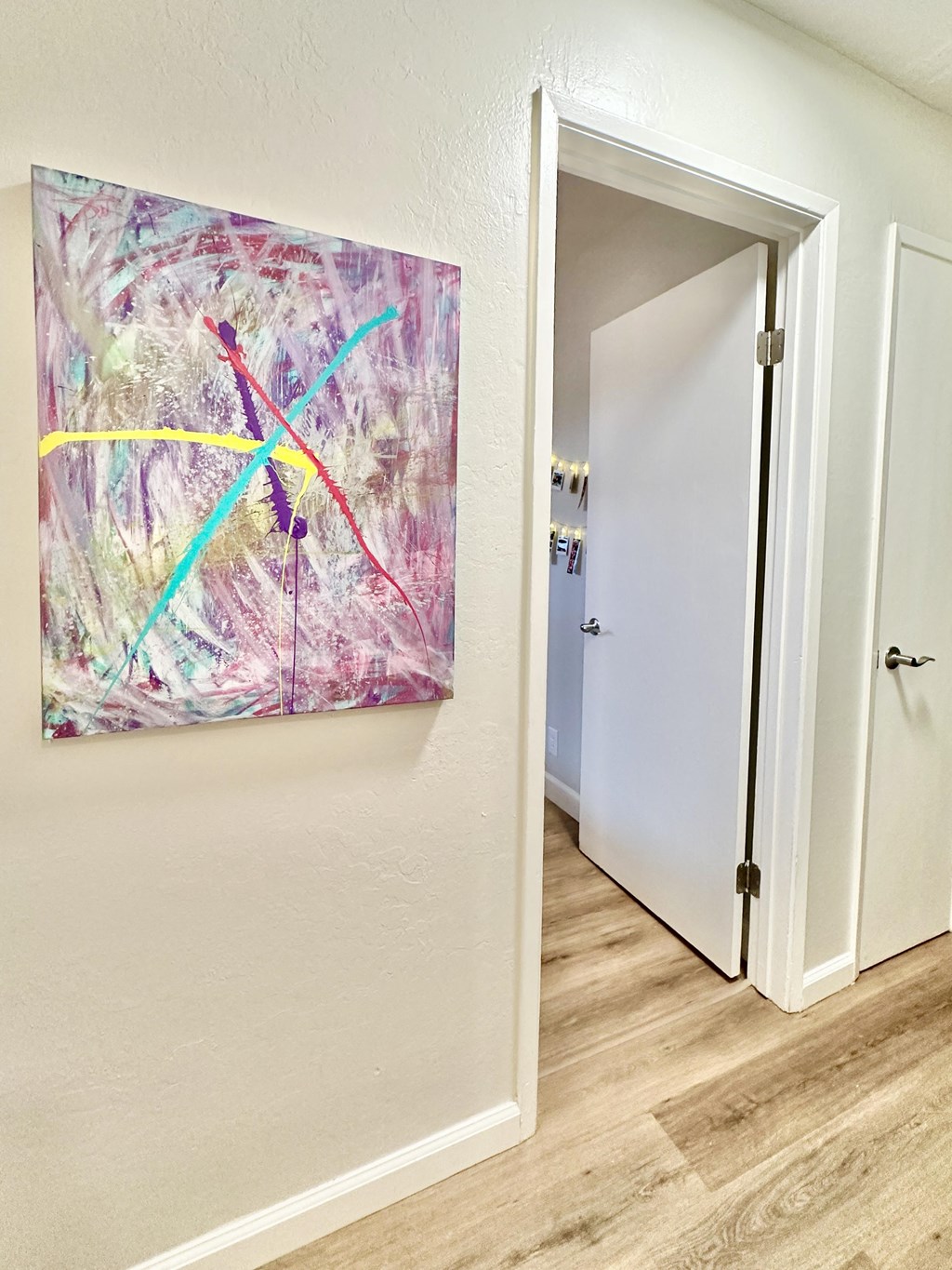 a hallway with a painting on the wall and an open door