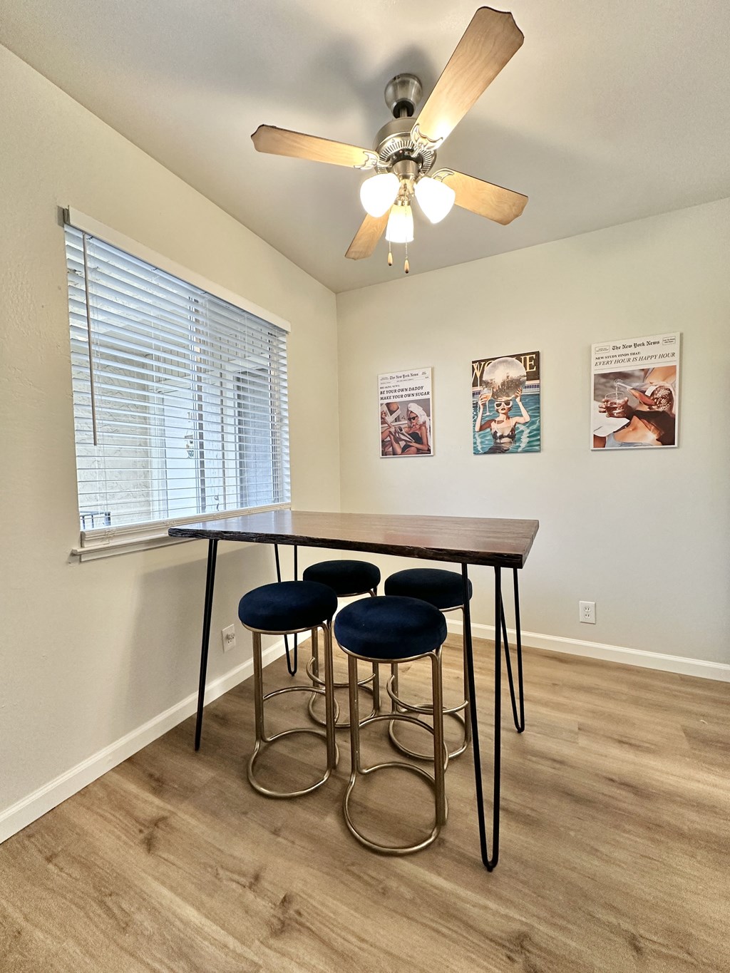 a dining room with a table and four stools under a ceiling fan