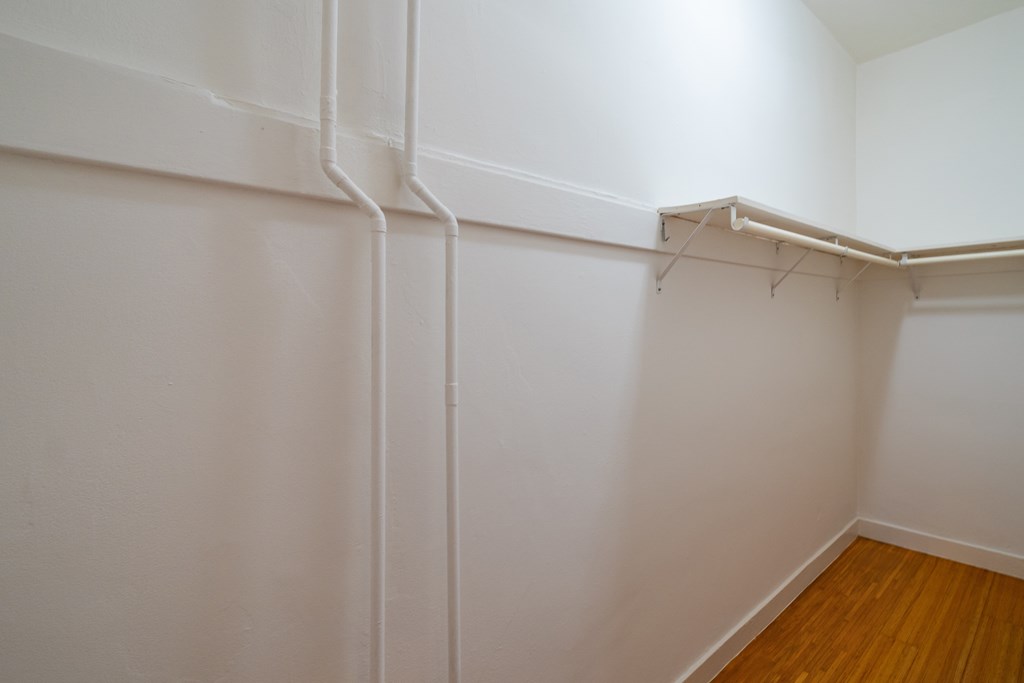 an empty room with white walls and wood flooring and a white walled closet