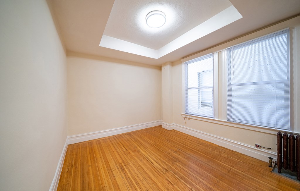 an empty living room with wood floors and a large window