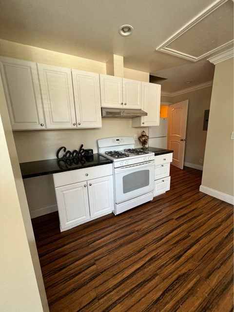 A kitchen with white cabinets and a black countertop.