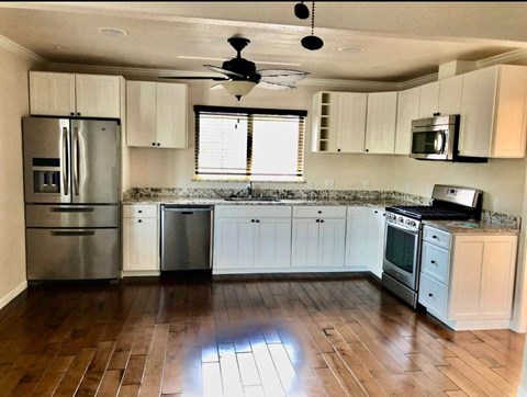 an empty kitchen with white cabinets and stainless steel appliances