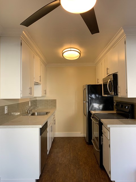 A kitchen with white cabinets and a black fridge.