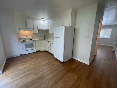 A kitchen with white cabinets and a white fridge.