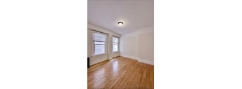 an empty living room with a wooden floor and two windows