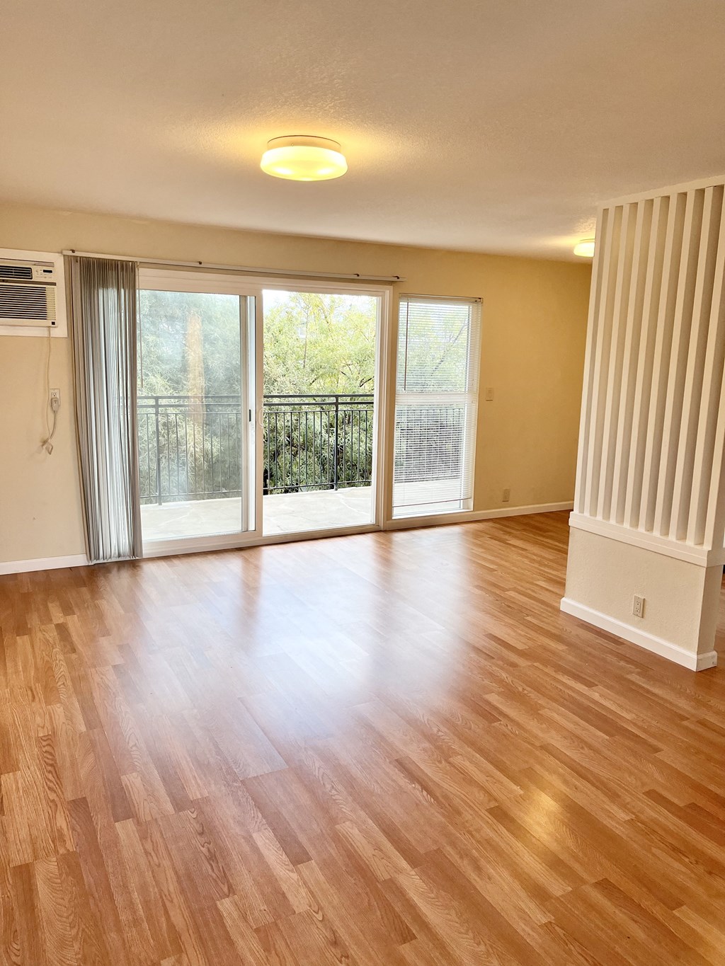 an empty living room with a sliding glass door and a balcony