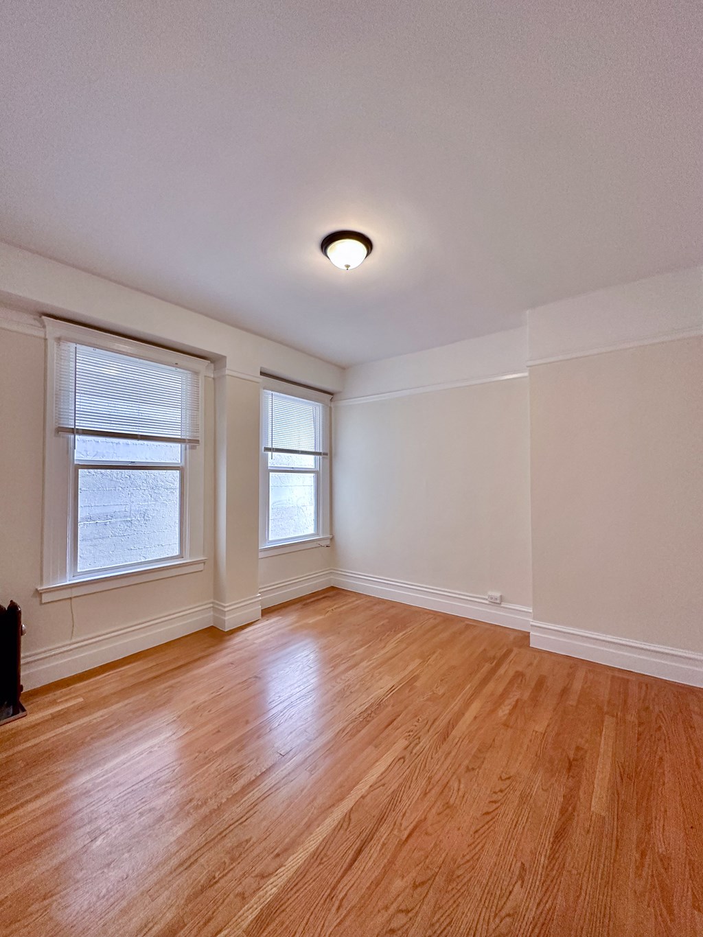 a Livingroom with two windows and a hardwood floor