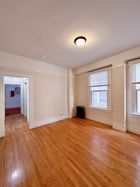 an empty living room with a hard wood floor and two windows