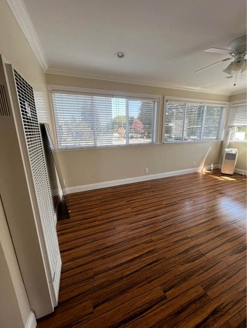 an empty room with a ceiling fan and three windows