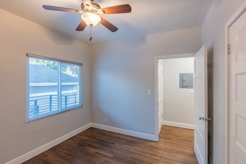 an empty bedroom with a ceiling fan and a window