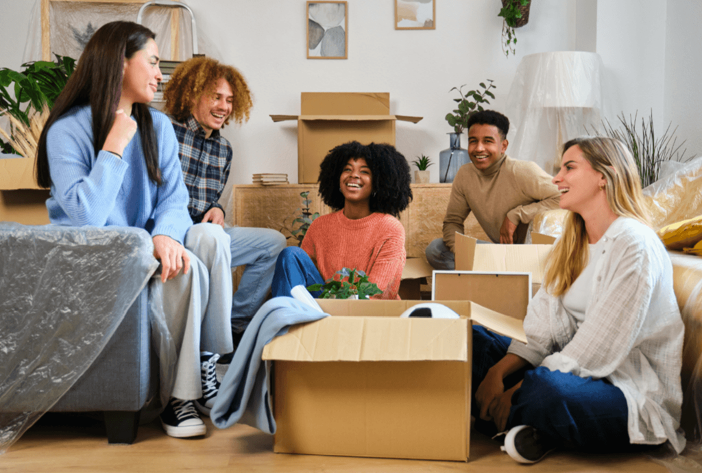 a group of people sitting in a living room with boxes