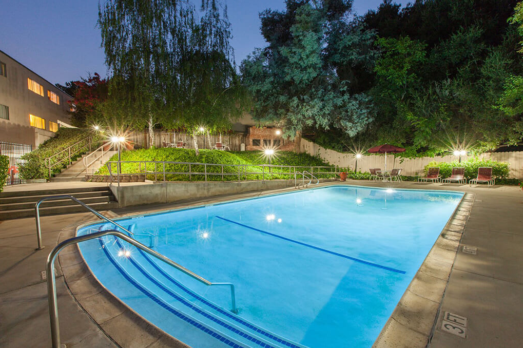 A swimming pool at night with lights on.