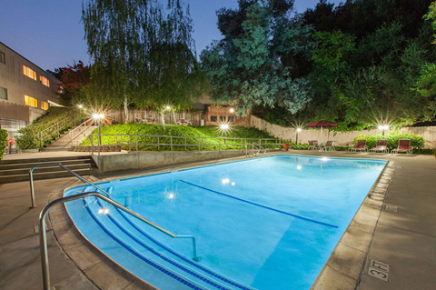 A swimming pool at night with lights on.