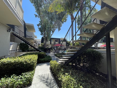 A pathway leads to a building with a black metal staircase.