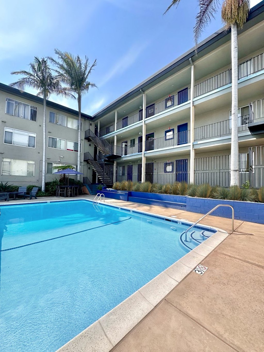 a large swimming pool in front of a building with palm trees