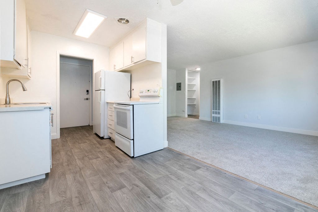 an empty kitchen and living room with white cabinets and appliances
