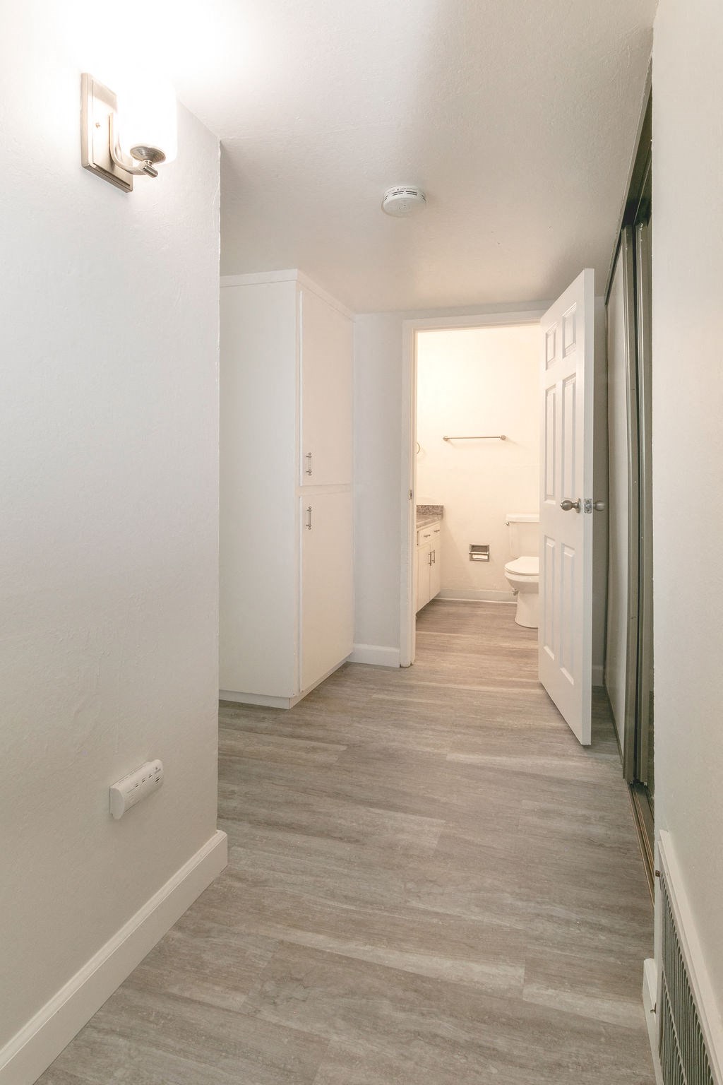 an empty hallway with a door open to a bathroom
